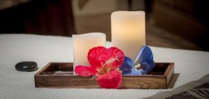 White candles with pink and blue flowers in wooden box